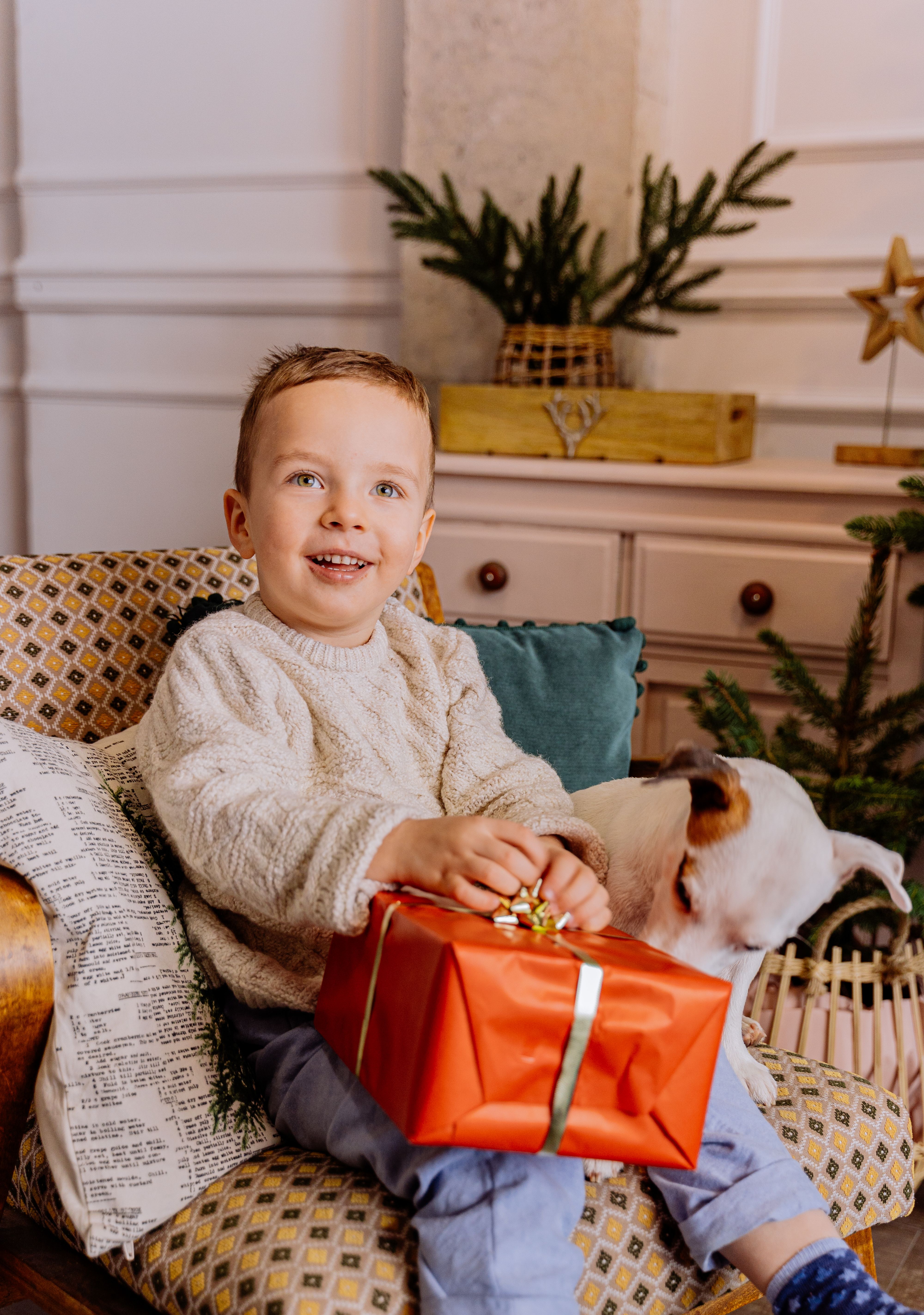 Young boy smiling with a wrapped gift in his lap