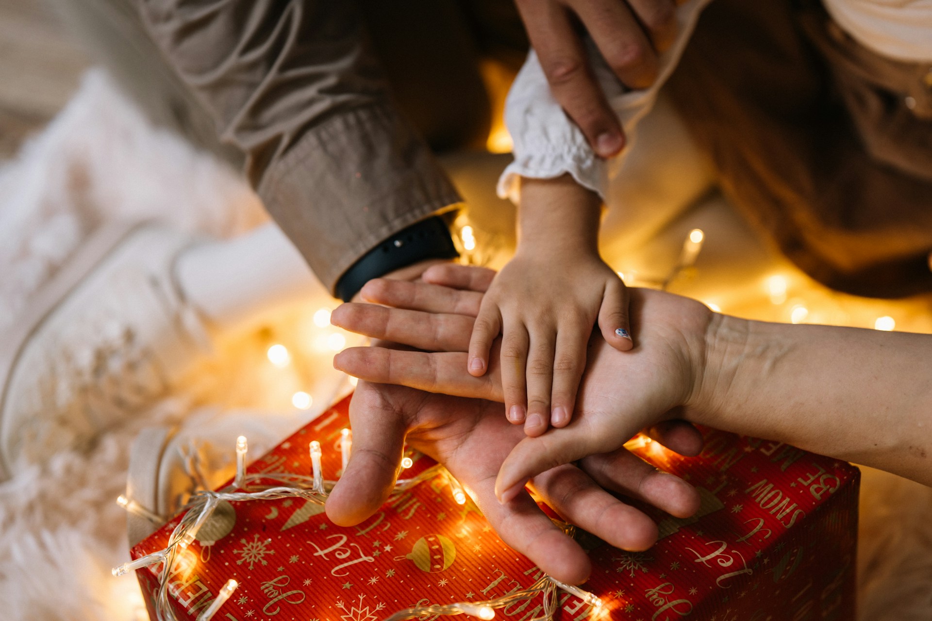 Hands of different generations resting together on a wrapped gift